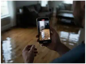 Homeowner uses phone to document damage caused by water as part of the filing process for insurance claims.
